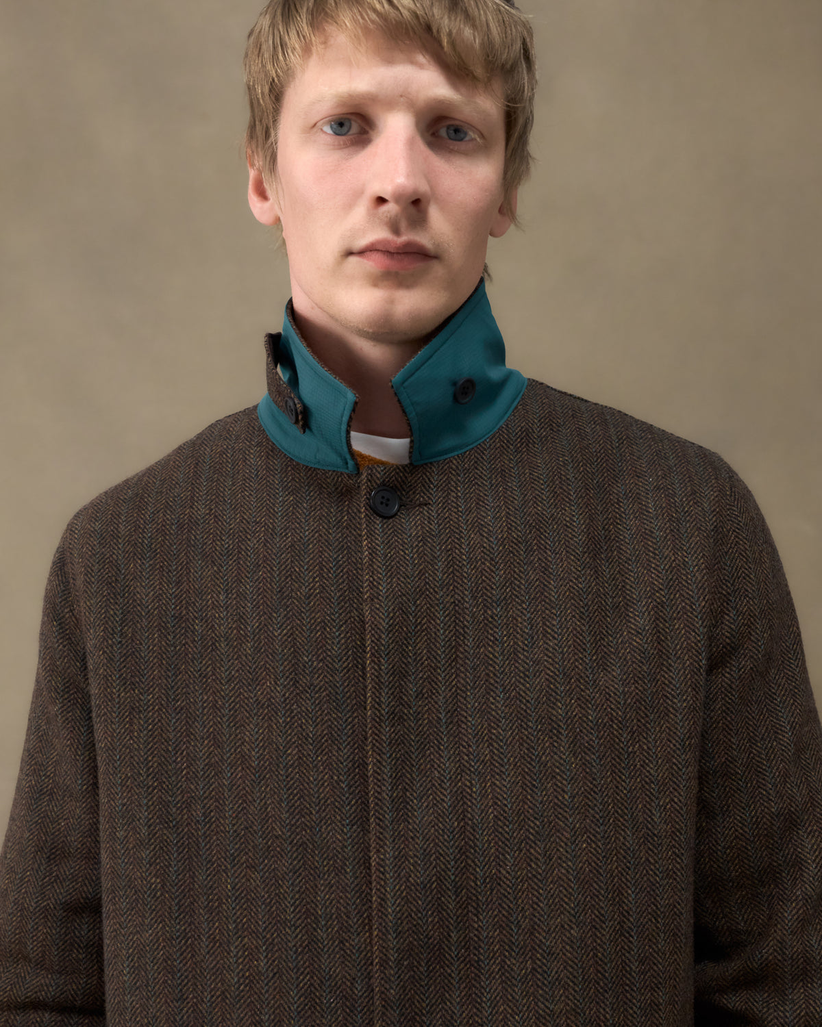 Close-up of the Fera Marwood Coat in Tweed Herringbone showing the raised storm collar with teal facing