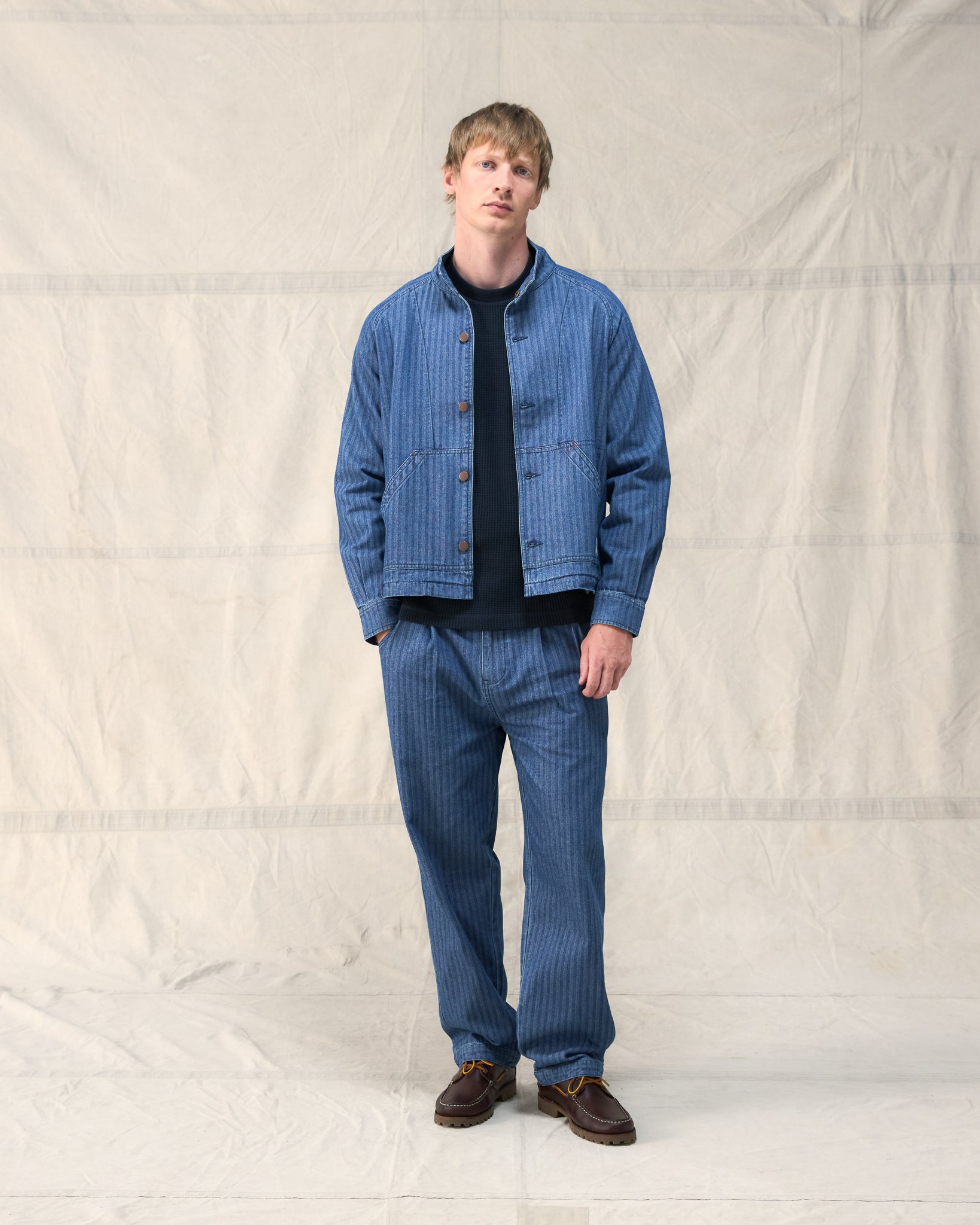 The Fera Uniform Jacket in striped denim, a button-up jacket with a stand collar.