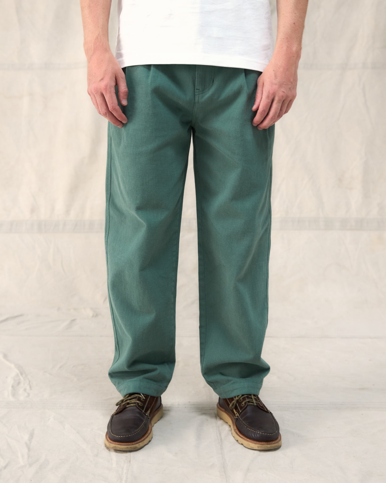 Our Fera Uniform Trousers are cut from a 250gsm washed green cotton and pair a wider, relaxed leg with refined double pleats at the waist.