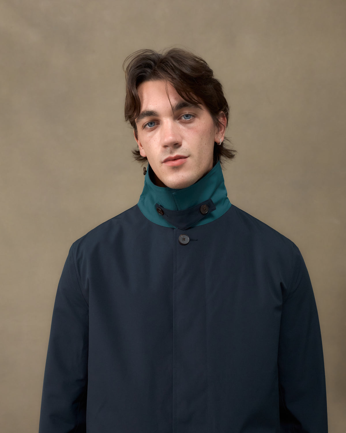 Close-up of the Fera Marwood Coat in Navy with the storm collar raised, showing the teal facing