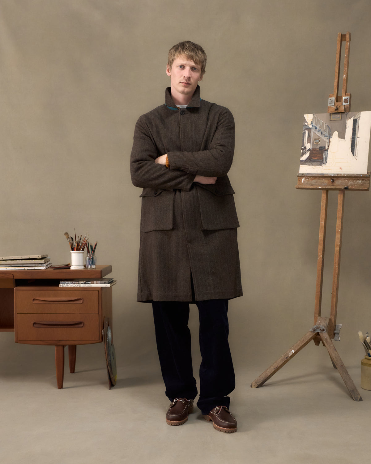Model wearing the Fera Marwood Coat in Tweed Herringbone with the storm collar raised, arms folded