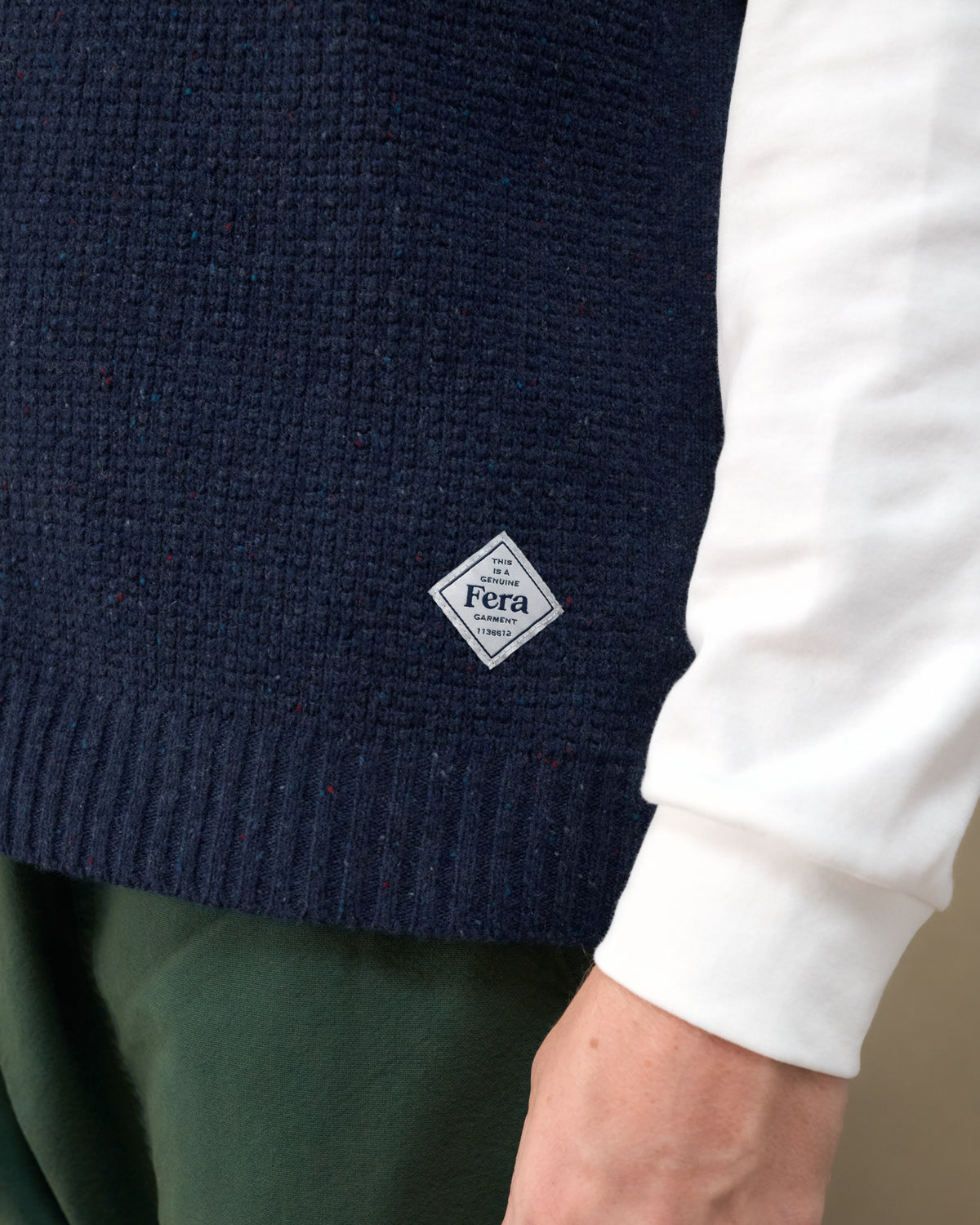 Close-up of the Fera Curlew Merino Vest in Navy showing the waffle knit and Fera hem label