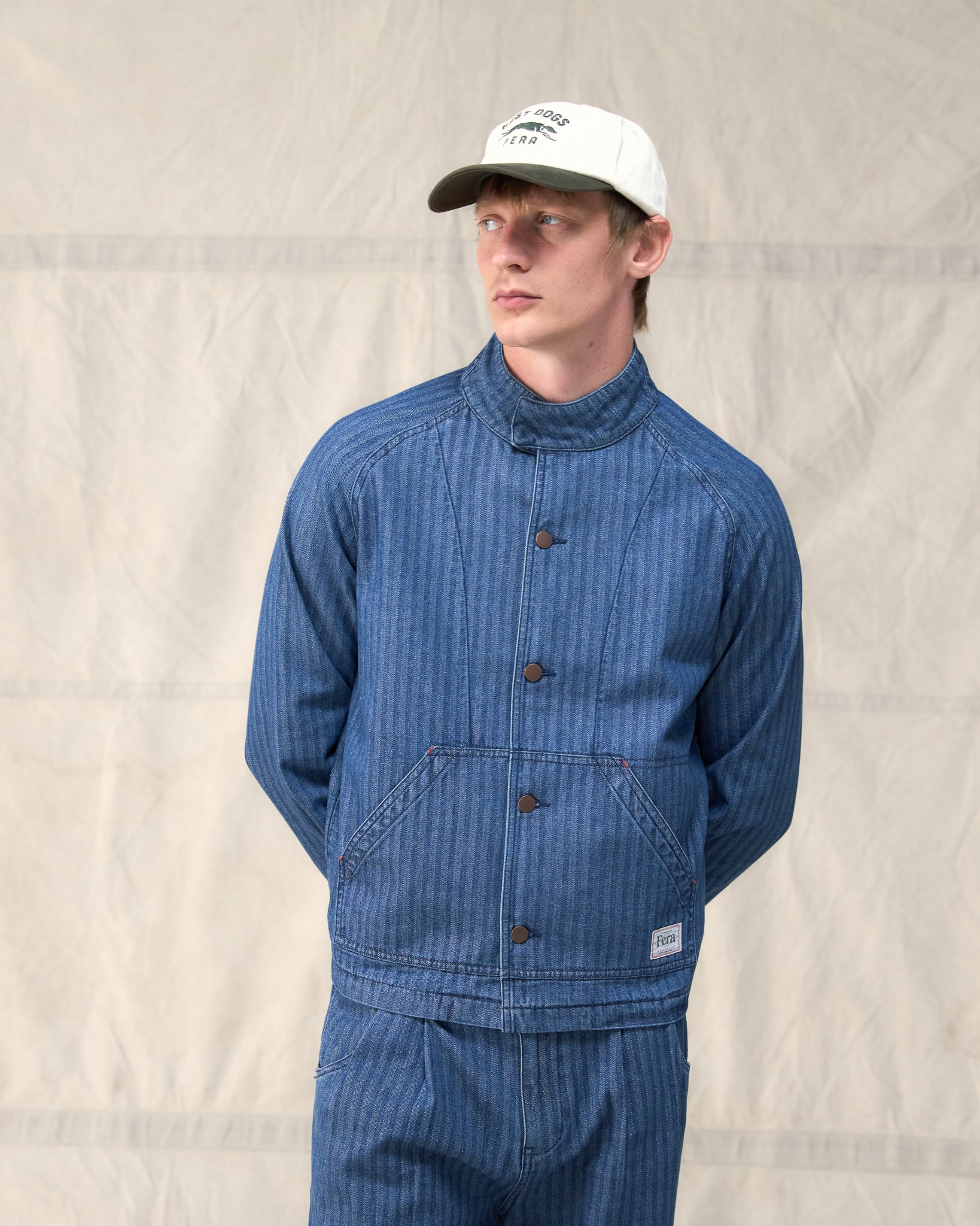 The Fera Uniform Jacket in striped denim, a button-up jacket with a stand collar.