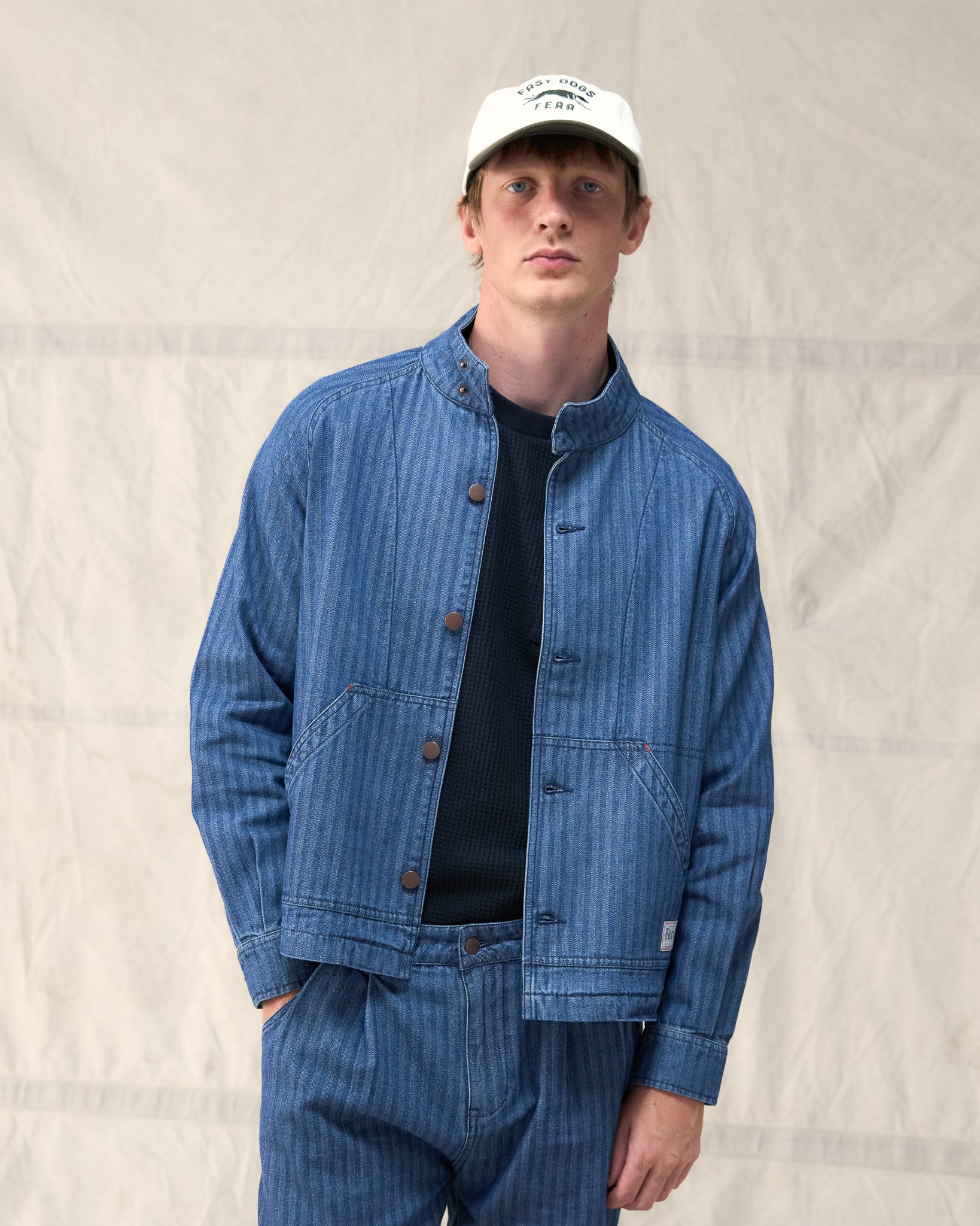 The Fera Uniform Jacket in striped denim, a button-up jacket with a stand collar.