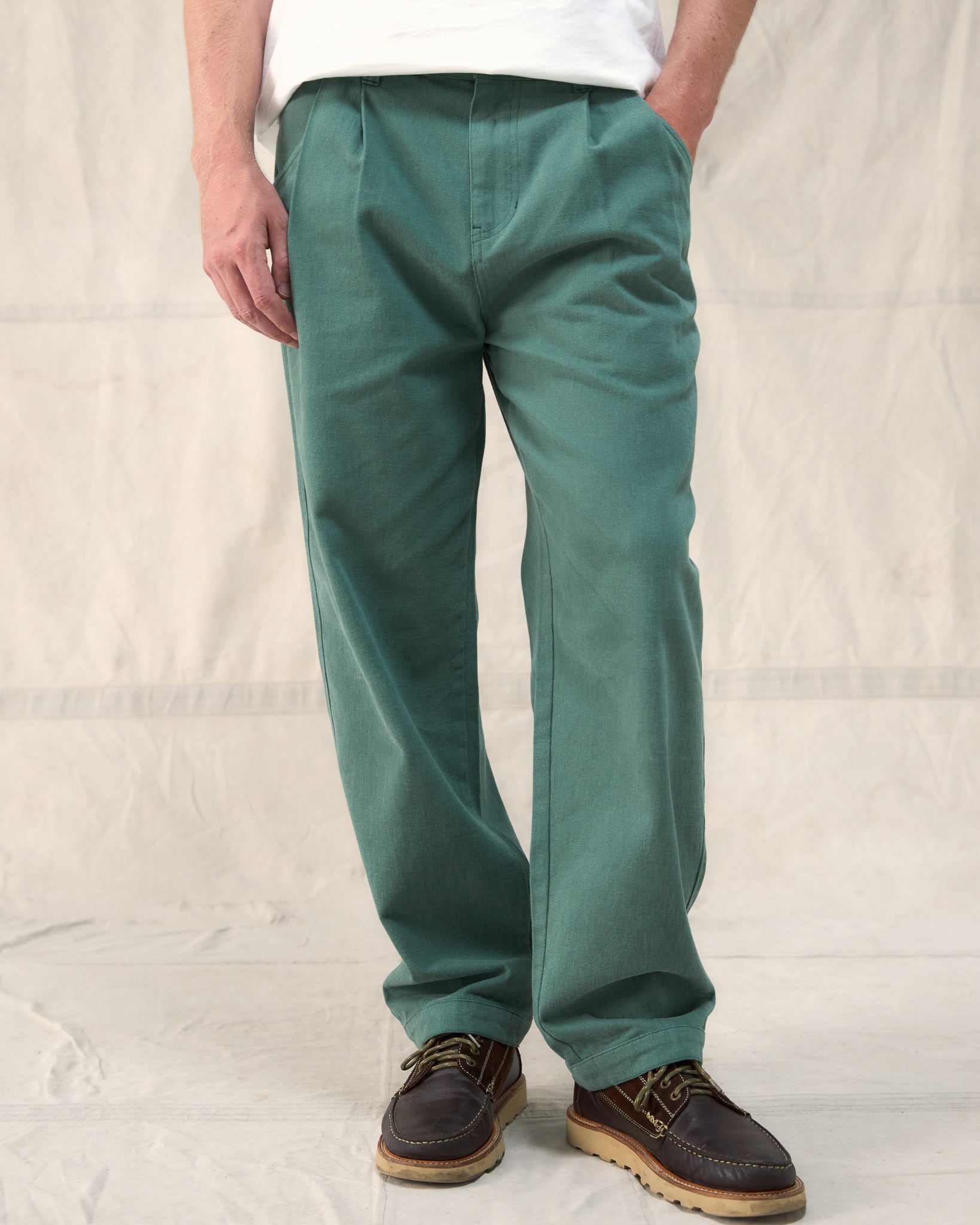 Our Fera Uniform Trousers are cut from a 250gsm washed green cotton and pair a wider, relaxed leg with refined double pleats at the waist.